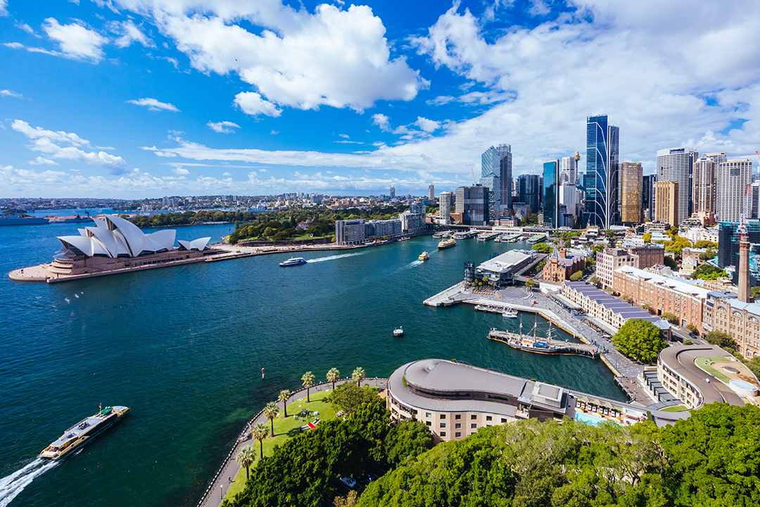 Panoramski pogled na Sydney z obalo, pristaniščem in mestnim središčem v ozadju.
